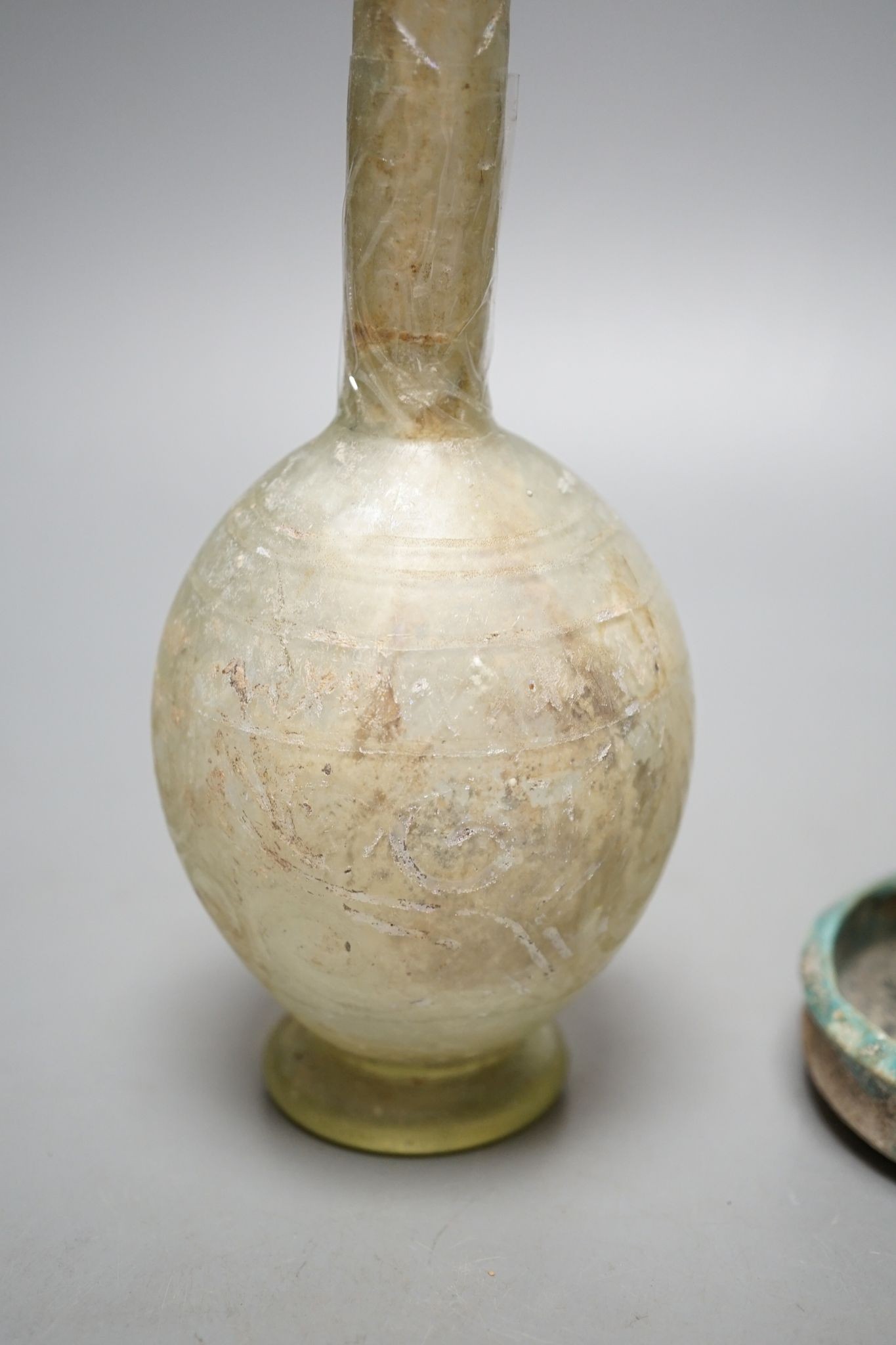 A Kashan oil lamp, 13th/14th century, and an early Islamic glass bottle., Bottle 22 cms high.
